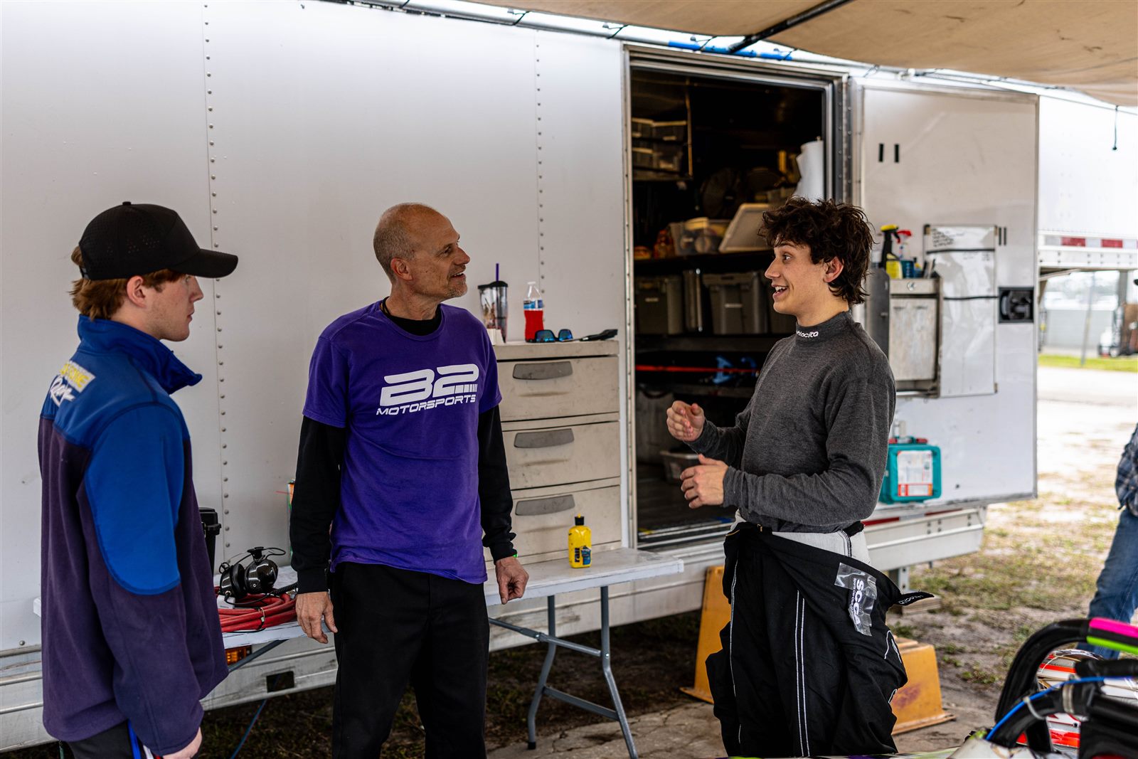 Cliff White talks with two B2 drivers at the team trailer, Sebring, January 2025